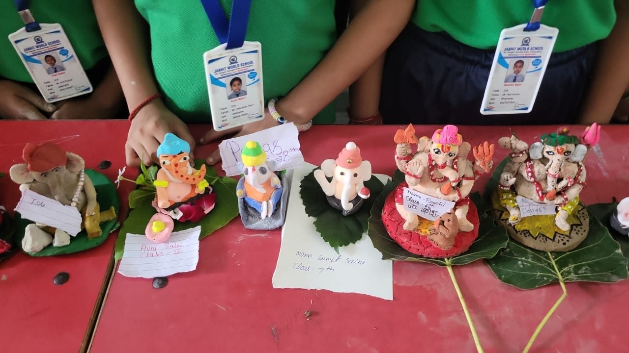 Close view of student-made clay models with name cards at Janhit World School
