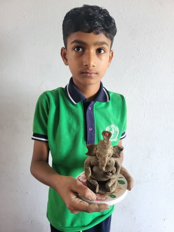A student of Janhit World School holding the clay Ganesh idol he modelled