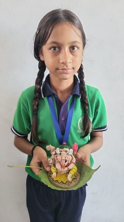 A student holding the clay Ganesh idol she made at Janhit World School
