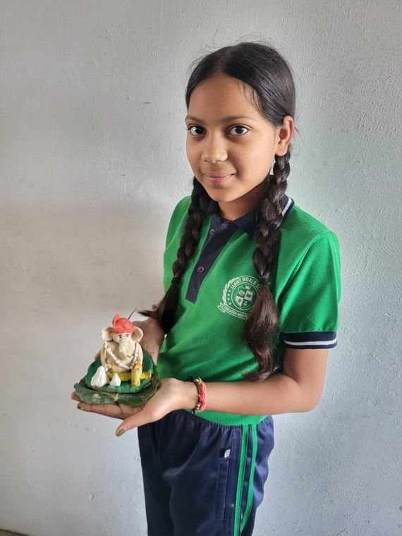 A student presenting her clay craft work at Janhit World School
